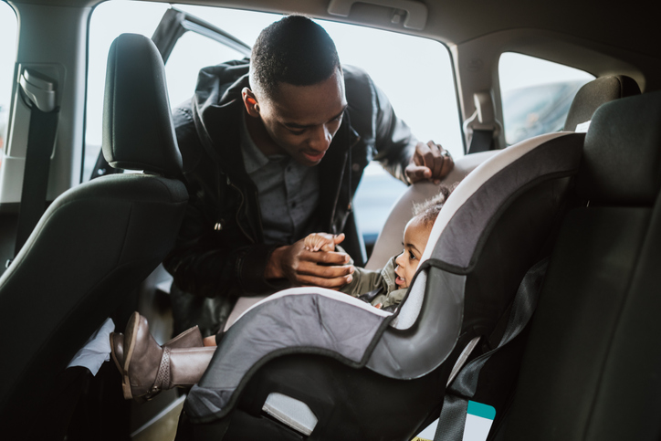 Loving Father Buckles Daughter in Car Seat